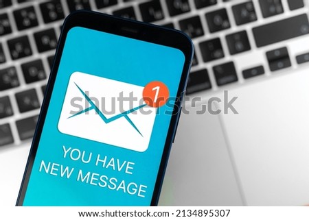 Mobile phone with new message icon and notification. Business communication and internet concept, laptop keyboard background
