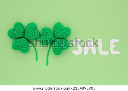 Two shamrock leaves and Sale lettering on green background. St. Patrick's Day Sale top view flatlay concept