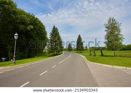 The paved road up the side of the trees, a freight train on a Sunny summer day Royalty-Free Stock Photo #2134903343