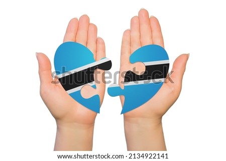 Woman hands are holding two parts of puzzle heart. National concept on white background. Botswana