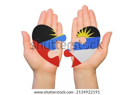 Woman hands are holding two parts of puzzle heart. National concept on white background. Antigua and Barbuda