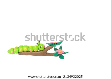 Plasticine statue of a green worm climbing a branch on a white background. Handmade clay plasticine