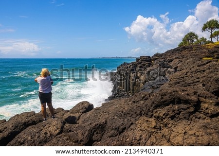 Woman looking at waves breaking on sea cliff