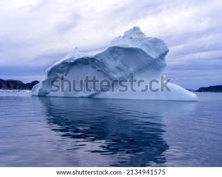 Large wedge shaped iceberg casting reflection in Twillingate Harbour during Spring