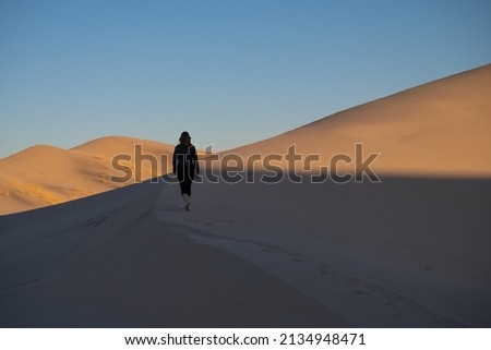 girl walking in dessert sand dunes sunset