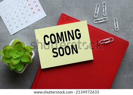 Coming Soon . notepad and yellow sticker on the table. sticker text