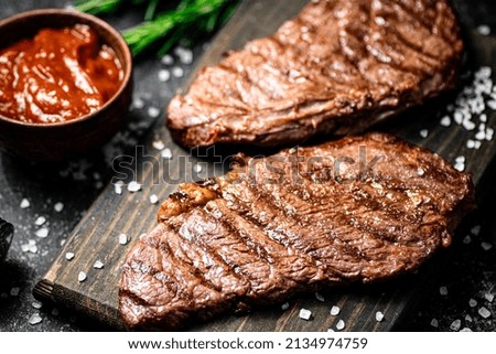 Grill steak on a wooden cutting board. On a black background. High quality photo