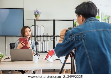 Behind the scene concept. Videographer discuss with young Asian female blogger to set up script before recording streaming live online with studio lighting. broadcasting vlogger. internet influencer.
