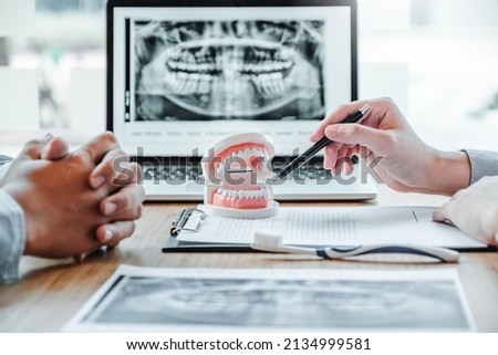 Dentist with male patient presenting discussing dental problems x-ray image film in dental office Royalty-Free Stock Photo #2134999581