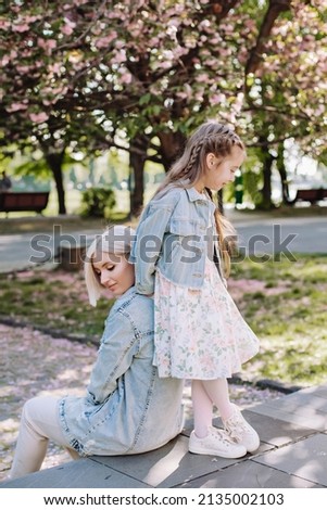 Family (mother and children) in spring city street with pink japanese cherry trees blossom (Uzhhorod City, Ukraine). Sakura blossomed. Young mother with her child have fun in the park near the sakura.
