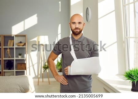 Portrait of young man with hand injury wear splint for fast recovery. Injured male with cast or sling on shoulder, have arm or shoulder trauma. Rehabilitation and healthcare concept. Royalty-Free Stock Photo #2135005699
