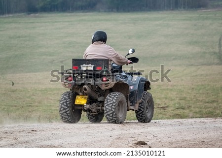 a quad biker with lights on riding his off-road quad bike along a stone track open countryside