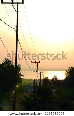 Portrait photo of the road to the beach with the silhouette of electric poles along the roadside
