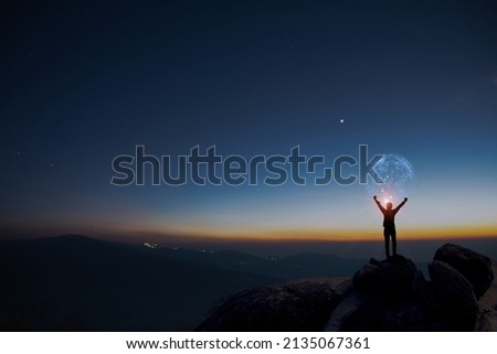 Earth in human hands. earth day. energy saving, Man raise hand up on top of mountain with sunrise sky and blue sky background, freedom travel adventure and feel good concept. Royalty-Free Stock Photo #2135067361