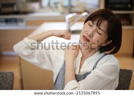A woman suffering from stiff shoulders  Royalty-Free Stock Photo #2135067895