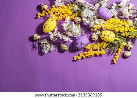 Spring composition with flowers, pastel eggs on purple very peri background. Hard light, dark shadow, happy Easter greeting card concept, flat lay, top view