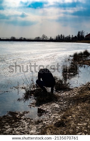 The photographer takes pictures by the pond in the winter in beautiful nature