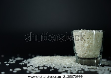 Stock photo of Close-up side views White rice grain called "Mentik Wangi" from Java, Indonesia in a small glass with black background. 