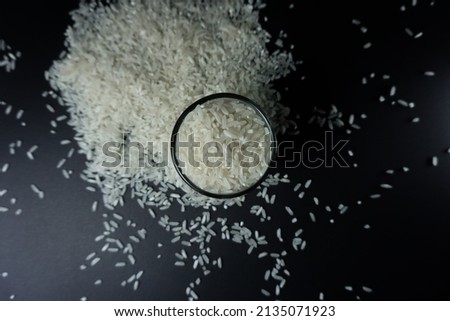 Stock photo of close-up top views White rice grain called "Mentik Wangi" from Java, Indonesia in a small glass with black background. 