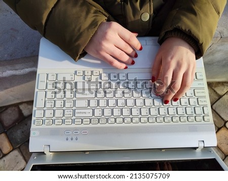 Girl holding the laptop on knees and typing on the keypad Royalty-Free Stock Photo #2135075709
