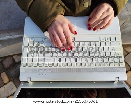 Closeup shot of a woman's hands typing on the keypad of the laptop computer on knees Royalty-Free Stock Photo #2135075961