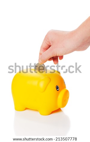 Yellow piggy bank is getting two euro coin from a hand on white background