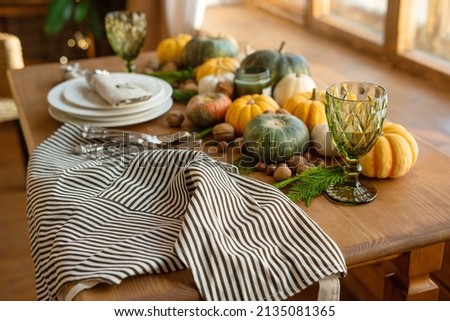 Festive Thanksgiving table. Apron, glass, pumpkins, nuts, plates and candles.
