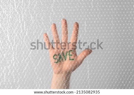 Social activism. The inscription Save is written on the palm of a human hand behind a transparent plastic bubble wrap. Save Planet concept. Male hand showing stop sign