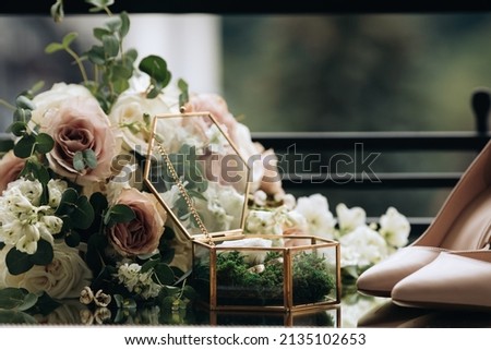 Gold wedding rings on a decorative green moss in a handmade glass box. Wedding accessories