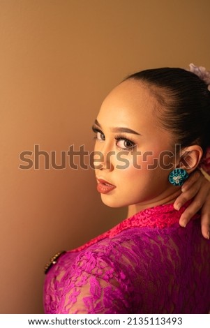 Rear Shoot of Young Asian women wearing traditional pink dresses called kebaya with tied black hair and beautiful make up 