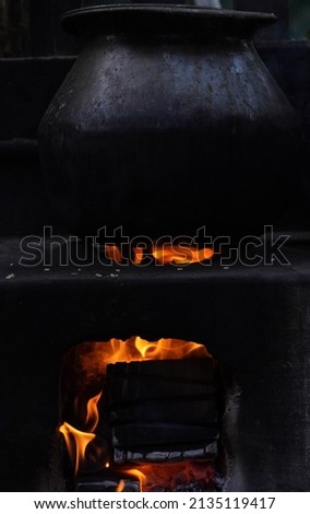 Hot heat and black charcoal. Cooking outdoors . Traditional pot in hot coals and ashes . Stock Photo