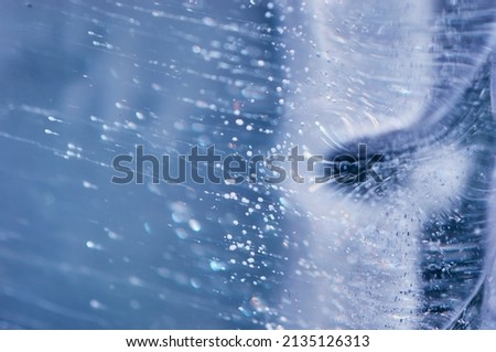 Air bubbles rising from the bottom froze in transparent blue ice. Ice pattern and texture. Optical distortion and refraction of light. Royalty-Free Stock Photo #2135126313