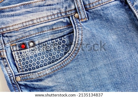 Texture of blue jeans with a beautiful front pocket. Seams, prints, rivets on the pocket close-up. Casual urban classic fashion tailoring clothing concept.