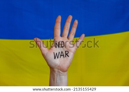 No war sign on female hand. Ukrainian flag background. Anti war Ukraine activist concept