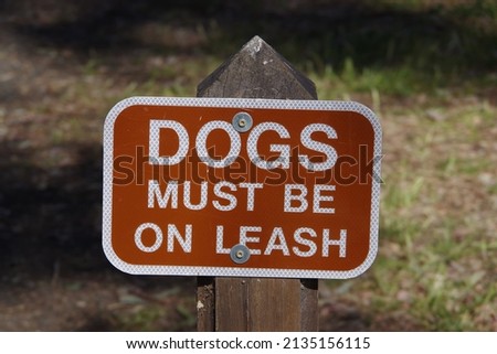 DOGS MUST BE ON A LEASH posted sign at a public park