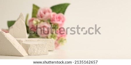 Empty stack of stones platform podium and rose flower bouquet on beige horizontal long background. Minimal empty display product presentation scene.