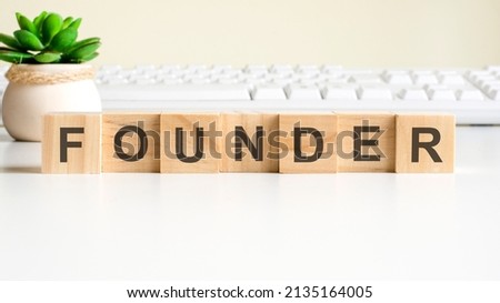 founder word made with wooden blocks. front view concepts, green plant in a flower vase and white keyboard on background