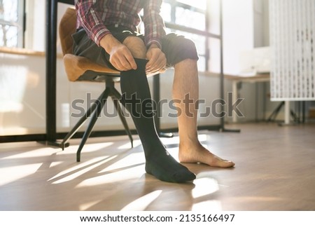 Man Putting On Medical Compression Stockings On Legs Royalty-Free Stock Photo #2135166497