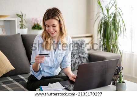 A young woman using a credit card at home to make a purchase or payment over the internet