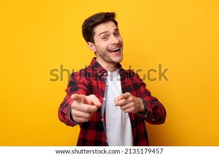 I Pick You. Portrait of excited young man pointing index fingers at camera, posing isolated over orange yellow studio background wall. Positive smiling adult male choosing and indicating