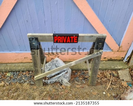 A wooden beam with private attached to it outside a building.