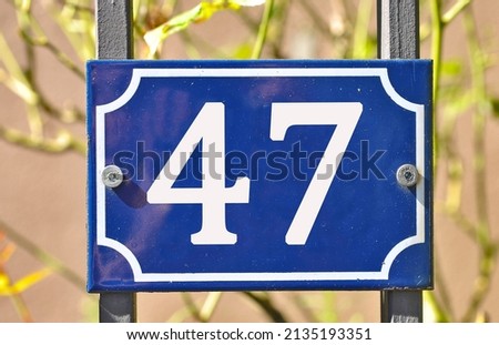A blue colored number plaque, showing the number forty seven (number 47)