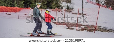 Boy learning to ski, training and listening to his ski instructor on the slope in winter BANNER, LONG FORMAT Royalty-Free Stock Photo #2135198971