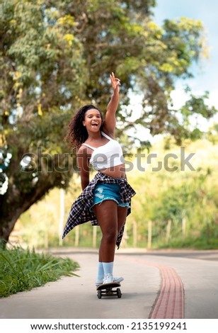 Young black woman smiling and skateboarding.
