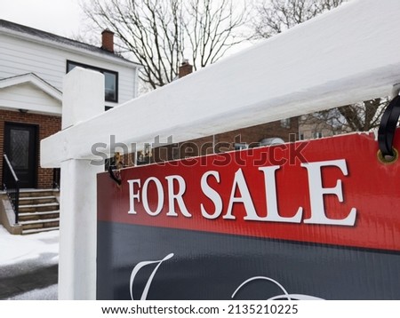 Sign for sale in front of a detached house in residential area. Real estate bubble, new listings, crash, hot housing market, overpriced property, overpaid, buyer activity concept. Selective focus.