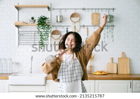 Asian young woman dancing in kitchen room. She happy and relaxing at free time on weekend