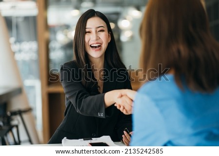 Portrait young Asian woman interviewer and interviewee shaking hands for a job interview .Business people handshake in modern office. Greeting deal concept Royalty-Free Stock Photo #2135242585