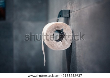 Bathroom tissue on anthracite tiled wall. Roll of toilet paper on a background.