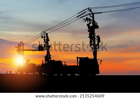 Silhouette of Electrician officer climbs a pole and uses a cable car to maintain a high voltage line system, Shadow of Electrician lineman repairman worker at climbing work on electric post power pole Royalty-Free Stock Photo #2135254609