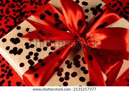A large gift box with red ribbons and confetti on a red background . The concept of a holiday, invitations, sales, invitations to a wedding or birthday. Black Friday.